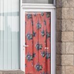 Schaufenstertür mit rotem Vorhang mit Blumen, etwas Sechziger-Vibes