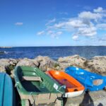 bunte kleine Boote an Felsen hinten meer und himmel