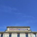 dominanter blauer Himmel, am unteren Rand Oberkante eines leicht verfallen aussehenden Hotels, Beschriftung auf dem Dach Armoric Hotel