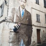 Street Art an Wand eines alten Hauses, ein überdimensionierter Herr mit Anzug und blauer krawatte