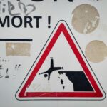 Warnschild vor Todsgefahr, sehr drastisch gezeichnetes Piktogramm, das kopfüber von der Klippe fällt